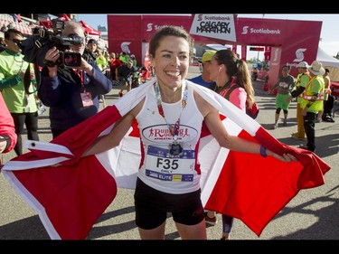 Emily Setlack carries the Canadian flag after winning the women's half-marathon during the Calgary Marathon at the Stampede Grounds in Calgary, Alta., on Sunday, May 29, 2016. There were 5k, 10k, 21.1k, 42.2k and 50k distances in the race, including the half-marathon national championships. Lyle Aspinall/Postmedia Network