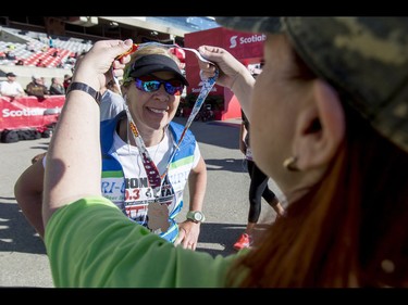 Natalie Burge receives a medal from Janice Cullen after  completing the 10-km portion of the Calgary Marathon at the Stampede Grounds in Calgary, Alta., on Sunday, May 29, 2016. There were 5k, 10k, 21.1k, 42.2k and 50k distances in the race, including the half-marathon national championships. Lyle Aspinall/Postmedia Network