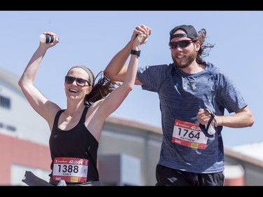 Karly Baxter and Matthew Kerslake cross the finish line hand-in-hand during the Calgary Marathon at the Stampede Grounds in Calgary, Alta., on Sunday, May 29, 2016. There were 5k, 10k, 21.1k, 42.2k and 50k distances in the race, including the half-marathon national championships. Lyle Aspinall/Postmedia Network