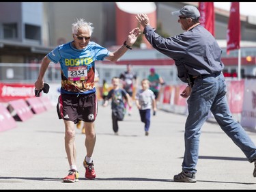 Gerald Millett, age 79, is high-fived while completing the Calgary Marathon at the Stampede Grounds in Calgary, Alta., on Sunday, May 29, 2016. There were 5k, 10k, 21.1k, 42.2k and 50k distances in the race, including the half-marathon national championships. Lyle Aspinall/Postmedia Network