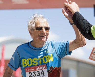 Gerald Millett, age 79, is high-fived while completing the Calgary Marathon at the Stampede Grounds in Calgary, Alta., on Sunday, May 29, 2016. There were 5k, 10k, 21.1k, 42.2k and 50k distances in the race, including the half-marathon national championships. Lyle Aspinall/Postmedia Network