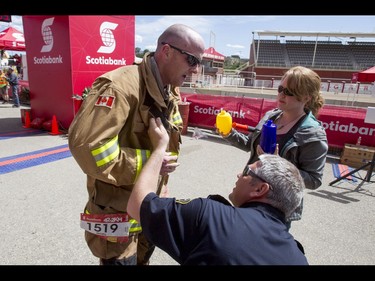 Olds firefighter Noel Darcy is immediately helped out of his full firefighter outfit by friend Dale Worth and wife Brianne Darcy after completing the Calgary Marathon at the Stampede Grounds in Calgary, Alta., on Sunday, May 29, 2016. Darcy wore full firefighting gear for the entire 42.2-km distance, and finished in a time of 5:25:03. There were 5k, 10k, 21.1k, 42.2k and 50k distances in the race, including the half-marathon national championships. Lyle Aspinall/Postmedia Network