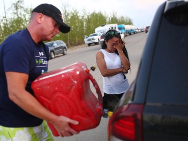 Marilou Wood fights back tears as husband Jim Wood fills up his car with gas after fleeing forest fires in Fort McMurray on May 4, 2016