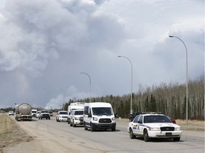 Police lead a convoy at the corner of Highway 63 and Highway 881 as a massive wildfire burns in Fort McMurray, Alta., on Wednesday May 4, 2016. A massive evacuation of Fort McMurray was held after a large wildfire struck the city.