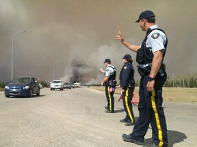 RCMP wave to cars as evacuees leave during convoy operations in Fort McMurray, Alberta on Friday May 6, 2016 in this image provided by the Alberta RCMP.