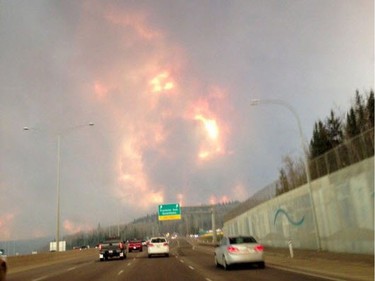 Smoke fills the air as people drive on a road in Fort McMurray, Alberta on Tuesday May 3, 2016 in this image provided by radio station CAOS91.1.