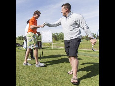 Olympic curler Ben Hebert (R) fist-bumps Olympic bobsledder Jesse Lumsden during the Shaw Charity Classic's annual Shootout at the Meadows at Canyon Meadows Golf and Country Club in Calgary, Alta., on Wednesday, May 18, 2016. The celebrity-and-media closest-to-the-pin driving contest is a precursor to the Shaw Charity Classic golf tournament set to begin Aug. 31. Lyle Aspinall/Postmedia Network