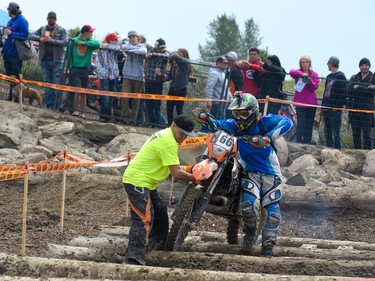 A volunteer helps competitor Steven Wnek pull his bike out of the log pit at the Redbull Chasing Limits Motocross competition in Calgary June 26, 2016.