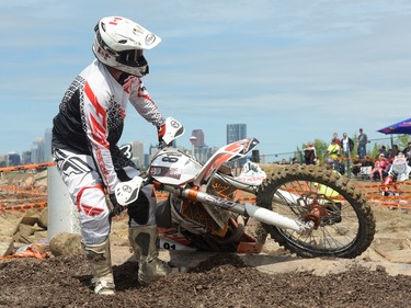 Todd Elliott attempts to haul his bike over logs at the Redbull Chasing Limits Motor Cross competition in Calgary on June 26, 2016. Many riders became trapped in the pit of logs and had to carry their bikes out.