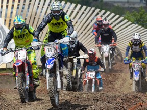 A pack of Motocross riders fights for the lead at the Redbull Chasing Limits Motor Cross competition in Calgary on June 26, 2016. Hundreds of people came to watch the competition, held at Wild Rose MX Park.