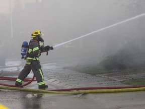 A firefighter battles a blaze in Airdrie that destroyed two homes and damaged another on Friday, June 17, 2016. (Richard Dering/Supplied)