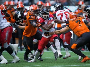 Calgary Stampeders' Roy Finch, centre, is tackled by B.C. Lions' Alex Bazzie (53) and Eric Fraser (7) during the first half of a pre-season CFL football game in Vancouver, B.C., on June 17, 2016.