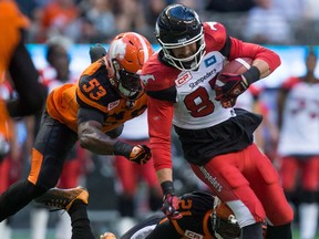 Calgary Stampeders' Simon Charbonneau-Campeau, front right, is brought down by B.C. Lions' Alex Bazzie, left, and Ryan Phillips after making a reception during the first half of a pre-season CFL football game in Vancouver, B.C., on Friday June 17, 2016.