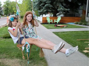 Gracie, left and Reilly McMillan hang out on the swing in front of their Calgary Bridgeland home on Wednesday June 22, 2016. City officials have said the swing has to go.