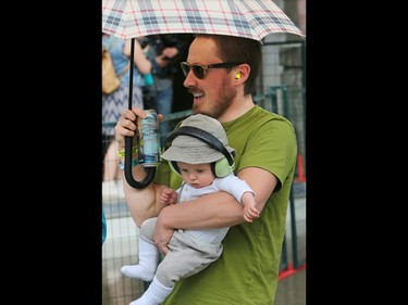 Drew Anderson holds his son Henry, 11 months, as he watches Suuns perform in Calgary's Olympic Plaza during the Sled Island Music Festival on Saturday June 25, 2016.