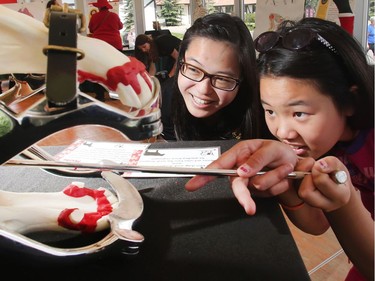 Rohanna Wong, left, studying for her doctorate of veterinary medicine, helps Chantelle Zhong, age 10, check out an equine dental work model at the University of Calgary Veterinary School display at Spruce Meadows on day four  of The National June 11, 2016.