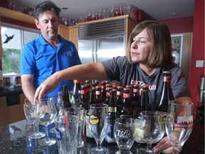 Mike Tessier watches as partner Bo Vitanov straightens beer glasses on the counter in their St Andrews Heights home Monday June 27, 2016. The couple run Artisan Ales, a beer importing company they say has been hit hard by changes in taxes imposed by the provincial government. (Ted Rhodes/Postmedia)