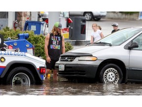 Dave Beddows watches as his van is towed from the flooded intersection of Braeside Drive and Southland Drive after he got swamped during the heavy downpour Tuesday afternoon June 28, 2016. (Ted Rhodes/Postmedia)
