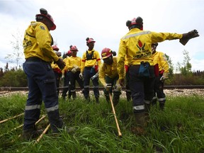A group of South African firefighters have a break as they work to mop-up hot spots in an area close to Anzac, just outside of Fort McMurray, Alberta on June 2, 2016.