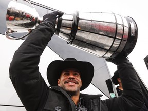 Jon Cornish lifts the Grey Cup as he returns to Calgary, Monday, Dec. 1, 2014, after defeating the Hamilton Tiger-Cats to win the 102nd Grey Cup. (THE CANADIAN PRESS/Jeff McIntosh)