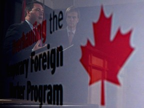 Employment Minister Jason Kenney, left, and Immigration Minister Chris Alexander are seen in a reflection at a news conference in Ottawa on Friday, June 20, 2014 on reforms to the Temporary Foreign Worker Program. (THE CANADIAN PRESS/Sean Kilpatrick)