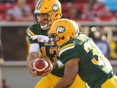Edmonton Eskimos quarterback Mike Reilly hands the ball off to John White during CFL action against the Calgary Stampeders at McMahon Stadium in Calgary, Alta.. on Saturday June 11, 2016. Mike Drew/Postmedia