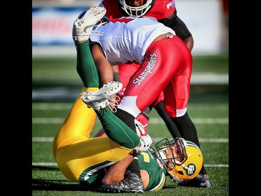 Edmonton Eskimos Mike Reilly takes a hit from Josh Bell of the Calgary Stampeders in CFL football in Calgary, Alta. on Saturday June 11, 2016. Al Charest/Calgary Sun/Postmedia Network