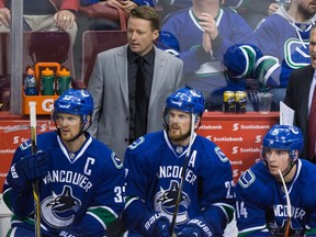 Vancouver Canucks' head coach Willie Desjardins, top right, shouts from the bench as assistant coach Glen Gulutzan, left, and players seated from left to right, Henrik Sedin, of Sweden, Daniel Sedin, of Sweden, Alex Burrows and Linden Vey watch the play during the third period of an NHL hockey game against the New York Islanders in Vancouver, B.C., on Tuesday January 6, 2015.