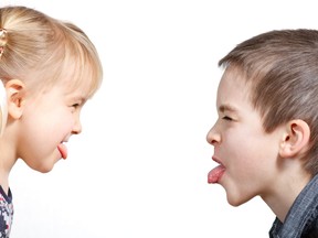 Young boy and girl sticking their tongues out at each other