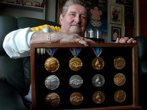 Jerry Joynt, Senior Vice President of Communications for the XV Olympic Winter Games at his NW Calgary home with a commemorative medal set he was presented at the end of the games.