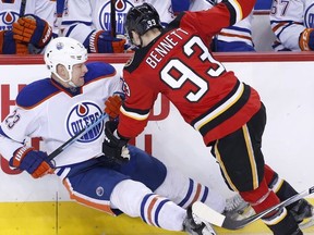 Edmonton Oilers' Matt Hendricks, left, is knocked down by Calgary Flames' Sam Bennett during third period NHL action in Calgary, Alta., Sunday Dec. 27, 2015.