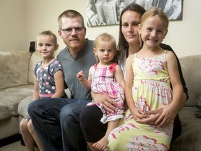 Nataya Pickersgill, age 21 months, sits with her sisters Saraya Pickersgill (L), 7, and Alayna Pickersgill, 5, and parents Trevor Pickersgill and Denaie McCarthy at home in Calgary, Alta., on Saturday, June 25, 2016. Two days earlier, Trevor saved Nataya from a septic tank at a highway rest stop near Maple Creek, Sask., after she fell in when the ground-level lid collapsed beneath her.