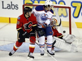 Edmonton Oilers' Ryan Jones, centre, scores on Calgary Flames goalie Joey Macdonald, right, as Patrick Sieloff looks on during first period NHL pre-season hockey action in Calgary, Alta., Saturday, Sept. 14, 2013.THE CANADIAN PRESS/Jeff McIntosh