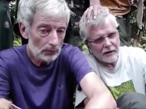 This file image made from undated militant video, shows Canadians Robert Hall, left, and John Ridsdel, right. With a black Islamic State group-style flag as a backdrop, Abu Sayyaf fighters beheaded Canadian hostage Hall on southern Jolo island on Monday, June 13, 2016, after a ransom deadline passed. (Militant Video via AP Video, File)