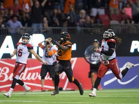 B.C. Lions' Chris Rainey, centre, outruns Calgary Stampeders' Rob Maver, back left, and Taylor Reed, right, to return a punt 72 yards for a touchdown during the second half of a CFL football game in Vancouver, B.C., on Saturday June 25, 2016.