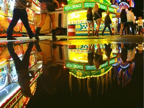 Stampede goers are reflected in a puddle left over from the afternoon's hail storm as the midway slowly winds down near midnight on July 4, 2015.