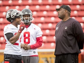 Joe Burnett (L) and Fred Bennett chat with defensive coordinator DeVone Claybrooks during the Calgary Stampeders training camp at McMahon Stadium in Calgary, Alta., on Thursday, June 2, 2016. The regular season begins on June 25, when the Stamps head to B.C.