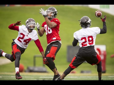 Joe Burnett (L) stops Kamar Jorden from making a catch near Jamar Wall (29) during the Calgary Stampeders training camp at McMahon Stadium in Calgary, Alta., on Wednesday, June 1, 2016. The regular season begins on June 25, when the Stamps head to B.C. Lyle Aspinall/Postmedia Network