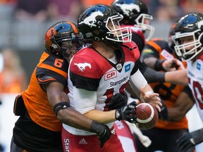 Calgary Stampeders' quarterback Bo Levi Mitchell, front, fumbles the ball as he's hit by B.C. Lions' T.J. Lee during the first half of a CFL football game in Vancouver, B.C., on Saturday June 25, 2016. B.C. recovered the ball on the play.
