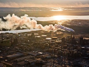 The setting sun reflects off a tailings pond behind Syncrude's oilsands upgrading facility north of Fort McMurray on June 18, 2013.