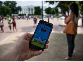 A man holds up his cell phone with a screen shot of the Pokemon Go game as a woman searches on her cell phone for a Pokemon in front of the White House in Washington, DC, July 12, 2016. Pokémon Go mania is sweeping the US as players armed with smartphones hunt streets, parks, rivers and elsewhere to capture monsters and gather supplies in the hit game. The free application based on a Nintendo title that debuted 20 years ago has been adapted to the mobile internet Age by Niantic Labs, a company spun out of Google last year after breaking ground with an "Ingress" game that merged mapping capabilities with play. As of July 11, 2016 Pokémon Go had been downloaded millions of times, jumping topping rankings at official online shops for applications tailored for smartphones powered by Apple or Google-backed Android software.   / AFP PHOTO / JIM WATSONJIM WATSON/AFP/Getty Images ORG XMIT: Pokemon G