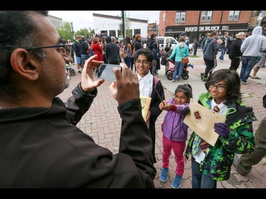 Feizal Merali gets a picture of kids Ki'an, Alaynna and Nehaan with their copy of the new Harry Potter book, a wand and a marauder's map in Calgary, Ab., on Sunday July 31, 2016. Hundreds of Potter fans thronged Kensington which was reimagined as Diagon Alley to celebrate the release of Harry Potter And The Cursed Child.  Mike Drew/Postmedia