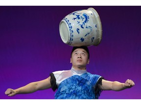 A performer from the Peking Acrobats rolls a porcelain jar across his arm-span at the 2016 Calgary Stampede in Calgary, Alta.