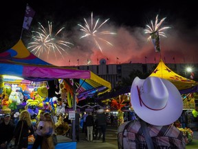 A visitor watches the fireworks display from the midway at the Calgary Stampede on Saturday. Telus Spark explores the science of the Stampede at Adults-Only Night on Thursday.