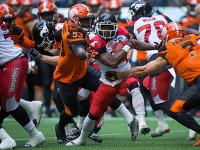 Calgary Stampeders' Roy Finch, centre, is tackled by B.C. Lions' Alex Bazzie (53) and Eric Fraser (7) during the first half of a pre-season CFL football game in Vancouver, B.C., on Friday June 17, 2016.