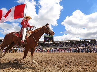 Riders ride with flags in the infield at the start of Day 3 of the Calgary Stampede Rodeo, Sunday July 10, 2016.