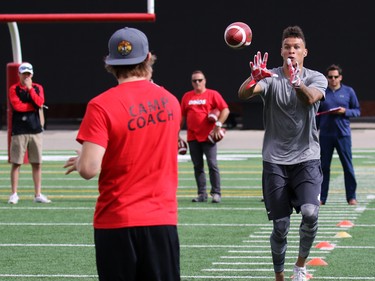 Jordan Heather throws balls for University of Calgary Dinos wide receiver Rashaun Simonise while Simonise is watched by six NFL scouts at McMahon Stadium in Calgary on Monday July 11, 2016. Simonise has been declared eligible for the NFL supplementary draft.