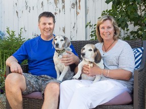 Tim and Jane Power are joined by their beagles Zak and Shiloh in the backyard of their Calgary home on Tuesday. The couple has fostered 18 dogs over the past few years.