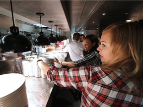 Servers work during the busy lunch hour at the downtown Earls outlet. Instead of the traditional tipping method, the rebranded location is testing a 16 per cent hospitality charge on all bills.