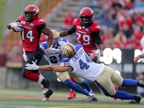 Calgary Stampeders Roy Finch, left, evades Winnipeg Blue Bombers Shayne Gauthier, right during during CFL action at McMahon Stadium in Calgary, Alta.. on Friday July 1, 2016. Leah hennel/Postmedia